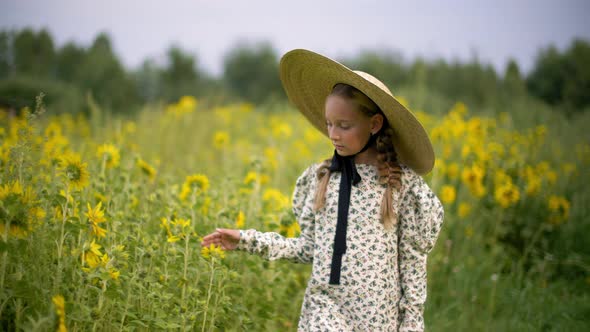 Cute Teen Girl in Hat Walking on Blossoming Sunflower Field