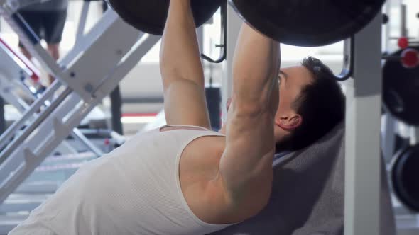 Handsome Muscular Man Doing Bench Press at the Gym