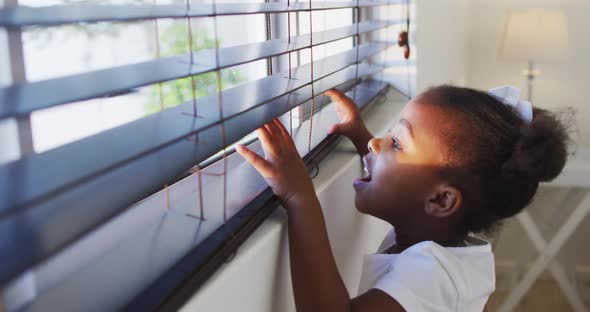 African american girl looking out the window at home