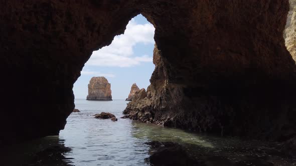 Viewing out the mouth of an Algarve sea cave to a limestone rock stack, Portugal.