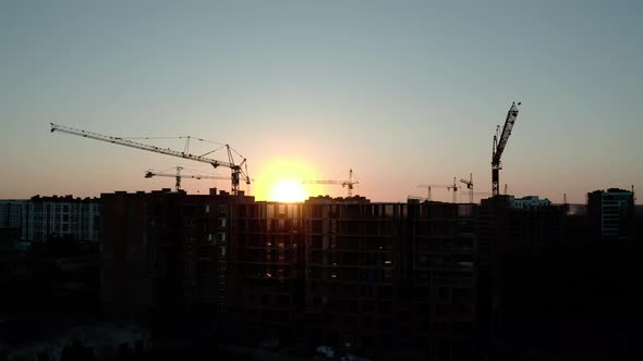 Aerial Drone View of Silhouette Construction Cranes in Sunset Light. Construction Site Building in alt