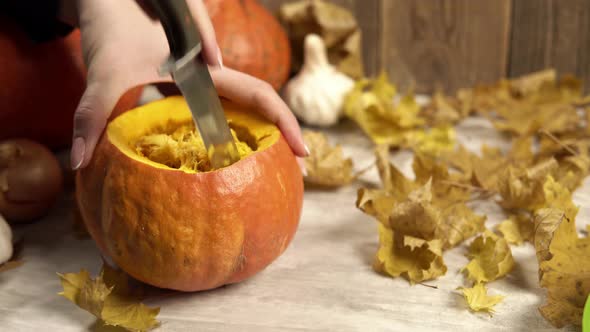 Girl Cleans Out the Inside of a Pumpkin with a Knife