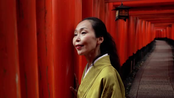 Elegant Japanese woman walking along a path lined with Torii Gates