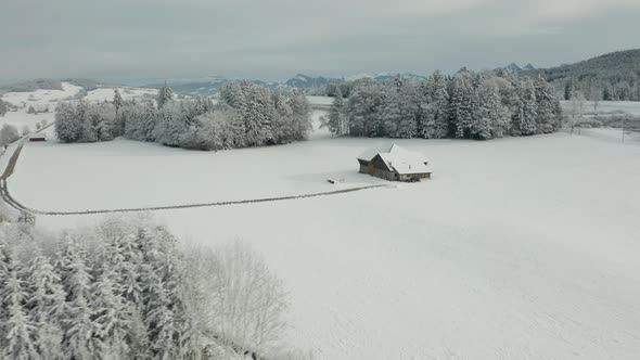 Aerial of small farmhouse in snow covered winter landscape