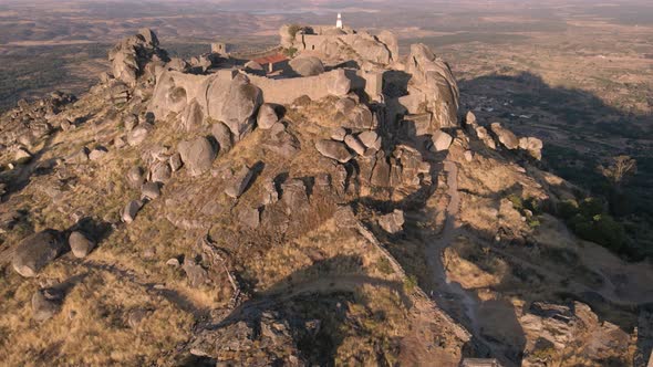 Drone flying over Monsanto castle ruins during sunrise, Portugal. Aerial forward tilt up reveal