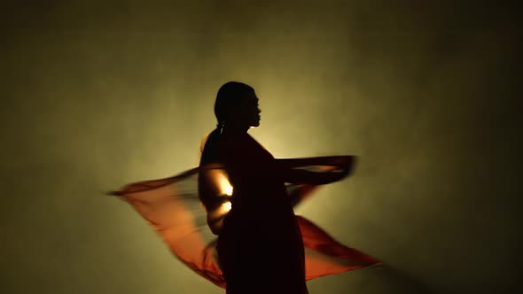 Silhouette a Young Girl Dancer in a Red Sari in an Indian Folk Dance on Stage in a Dark Studio with
