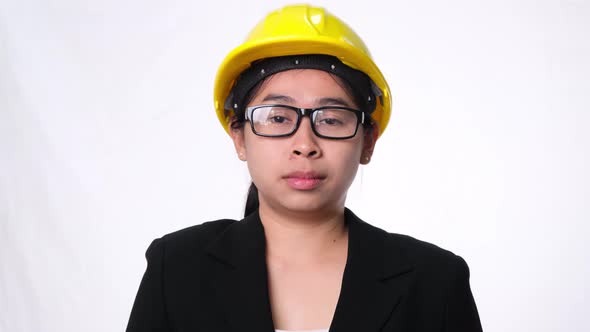 Female technician in helmet standing thumbs down, showing disapproval on white background.