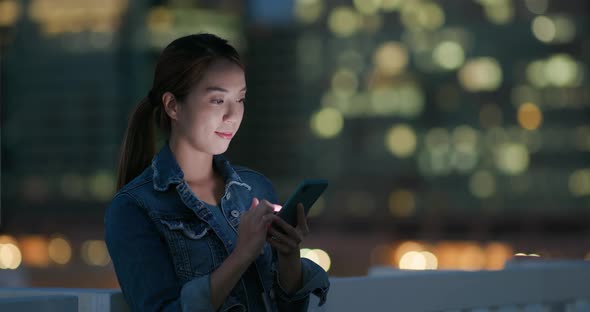 Woman use of mobile phone in city at night