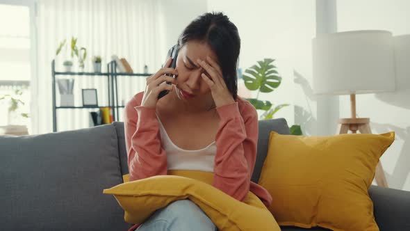 Young Asia lady sitting on sofa talk with friend and get bad news at home