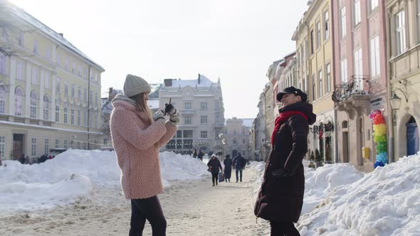Two Young Smiling Women Tourists Bloggers Taking Photos Portrait on Mobile Phone on City Street
