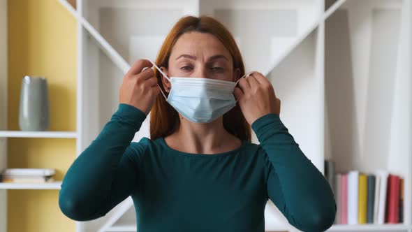 Young Woman Takes Off Medical Mask at Home. Health Care and Medical Concept. Close Up