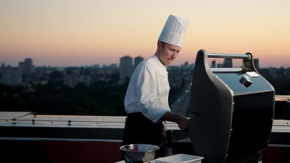 A professional Chef prepares a barbecue on the rooftop of a skyscraper. An expensive restaurant