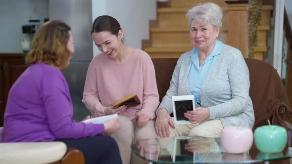 Laughing Multigenerational Caucasian Women Watching Photos Talking Resting Indoors on Weekend