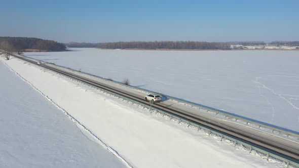 Aerial Shot of Car Riding Through Snow Covered Road Near Frozen Lake