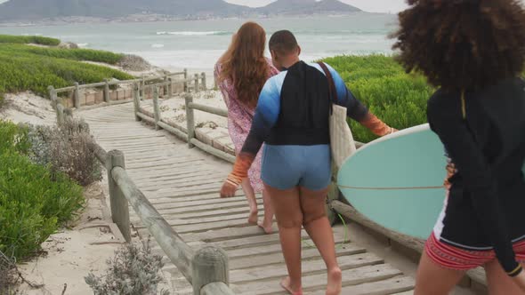 Diverse group of happy female friends going to the beach holding surfboards