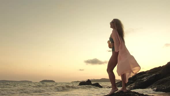 Woman Stand on a Reef Rock Stone in Sea on Sunset