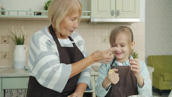 Grandmother and Granddaughter Having Fun in Kitchen Cooking Laughing Making Biscuits