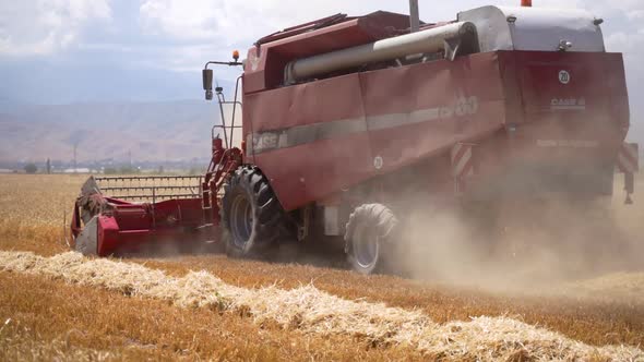 Slow motion of combine harvester working on a barley field on sunny summer day