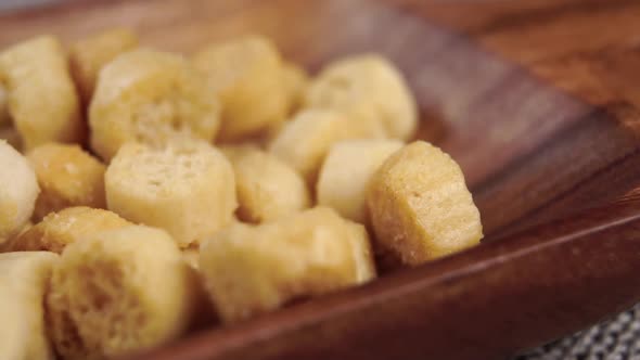 Round small bread croutons falling on a wooden kitchenware. Crunchy ingredient. Macro