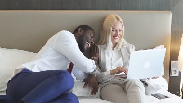 Beautiful Multiethnic Family Spends Time on a Business Trip, Watching News on Laptop