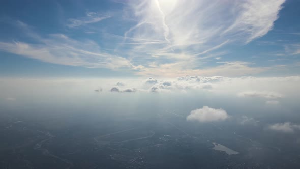 Aerial View From Airplane Window at High Altitude of Distant City Covered with Layer of Thin Misty