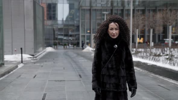 Rich Brunette Woman Dressed Fur Coat is Walking in Big City at Winter Strolling in Business District