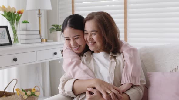 Asian family mother daughter give hug cuddle embrace at home sofa.