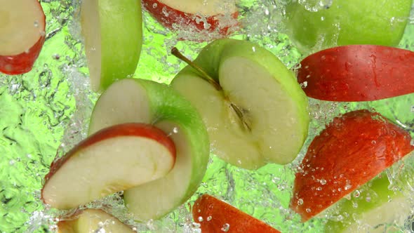 Super Slow Motion Shot of Red and Green Apple Cuts Falling and Splashing Into Water at 1000Fps