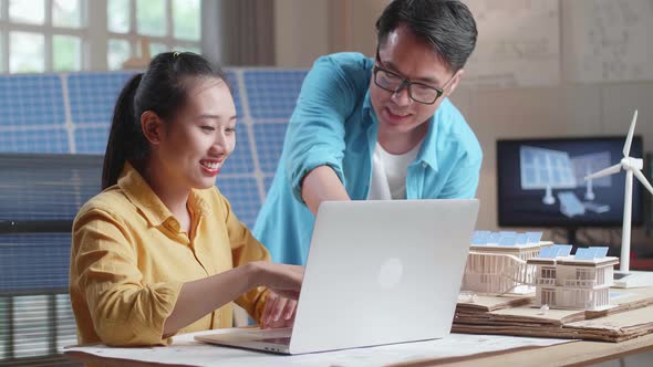 Asian Man And Woman Discuss About Work On A Laptop Next To The Model Of A Small House