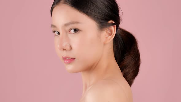 Close up Beauty shot of Beautiful Asian girl looking at camera isolated on pink background