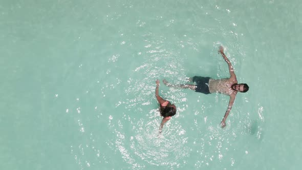 An Aerial Shot of a Young Couple Floating on Surface of Dead Sea Water and Enjoying Summer Sun and