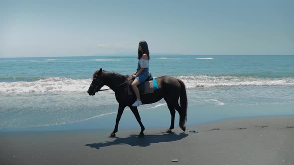 Cute Chinese Teenager Rides a Horse On The Beach In Bali