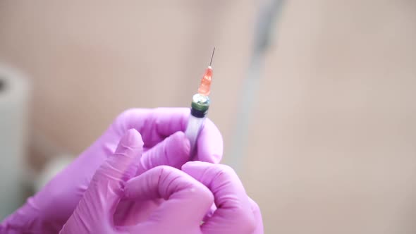 Close up of cosmetician s hand preparing a syringe for injection. Blur.