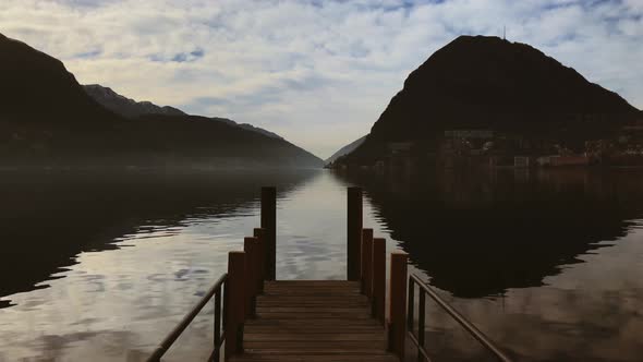 Quiet lake point of view of a dock pier with mountains background, loneliness and isolation concept