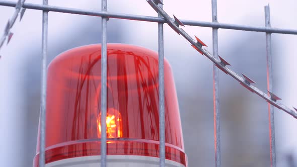 Warning Flashing Lights of Signalization at a Day. Barbed Wire Fence with Red Alarm Light. Rotating