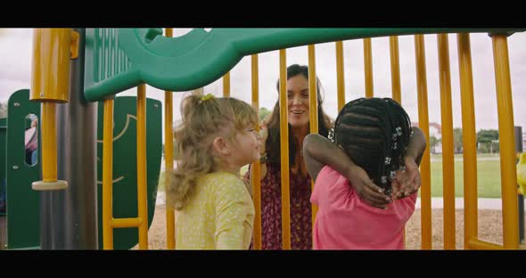 Woman Playing Peekaboo with Two Little Girls at Playground