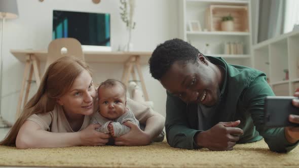 Happy Multiethnic Spouses Making Selfie with Child