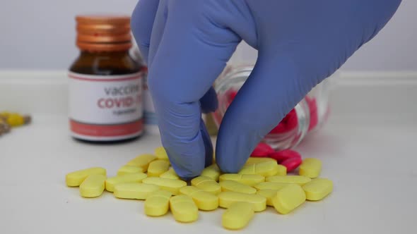 View of picking one yellow tablet from bunch of tablets with glass bottle around