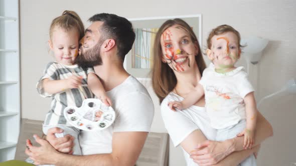 Positive Young Parents Holding Their Beautiful Daughters in Hands