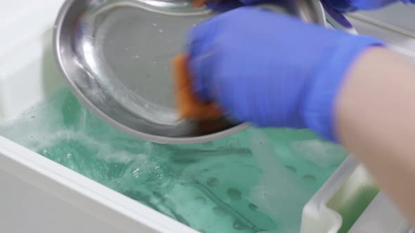 Nurse's Hands Is Washing Dental Instruments and Metal Tray in Disinfectant Solution.