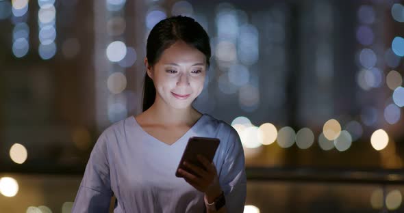 Woman use of smart phone in city at night