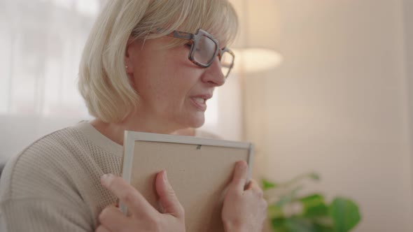 Shot of old man elderly looking at frame of photograph then hug with sadness.