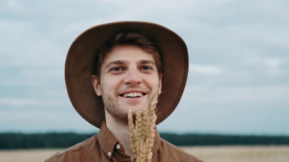 Close Up of Farmer Holding a Spikelet with a Brush of Wheat or Rye in His Hands at Sunset Looking