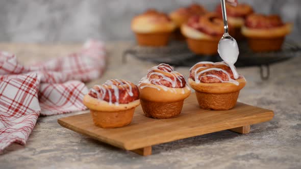 Pouring Icing Over Swirl Buns with Jam