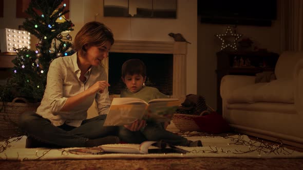 Mother reading book with son on Christmas eve