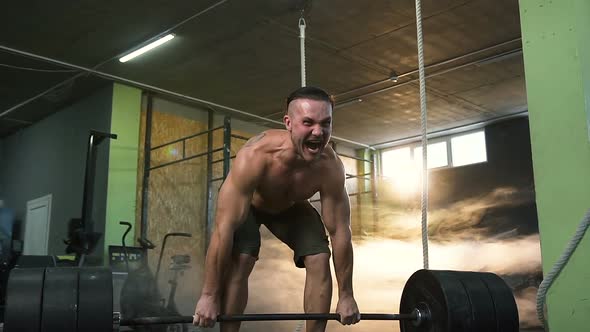 Young Strong Man Screaming and Doing Deadlift Exercise at Gym