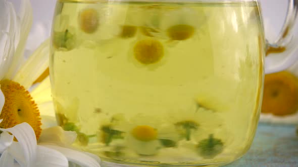 Brewing a herbal tea from chamomile in a glass jar.