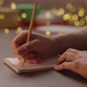 Orbit Shot of Man Writes New Year Goals in Notepad with a Pencil Under Warm Light in the Evening - VideoHive Item for Sale