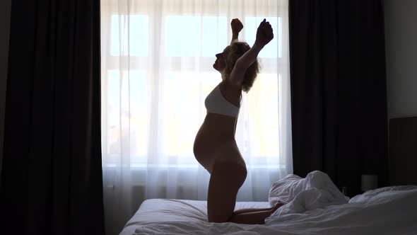 Young Pregnant Woman Stretching And Waking Up On Bed At Home