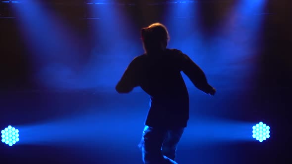 Silhouette of a Talented Young Girl Hip Hop Dancer. Hip Hop Street Dance on a Stage in Dark Studio